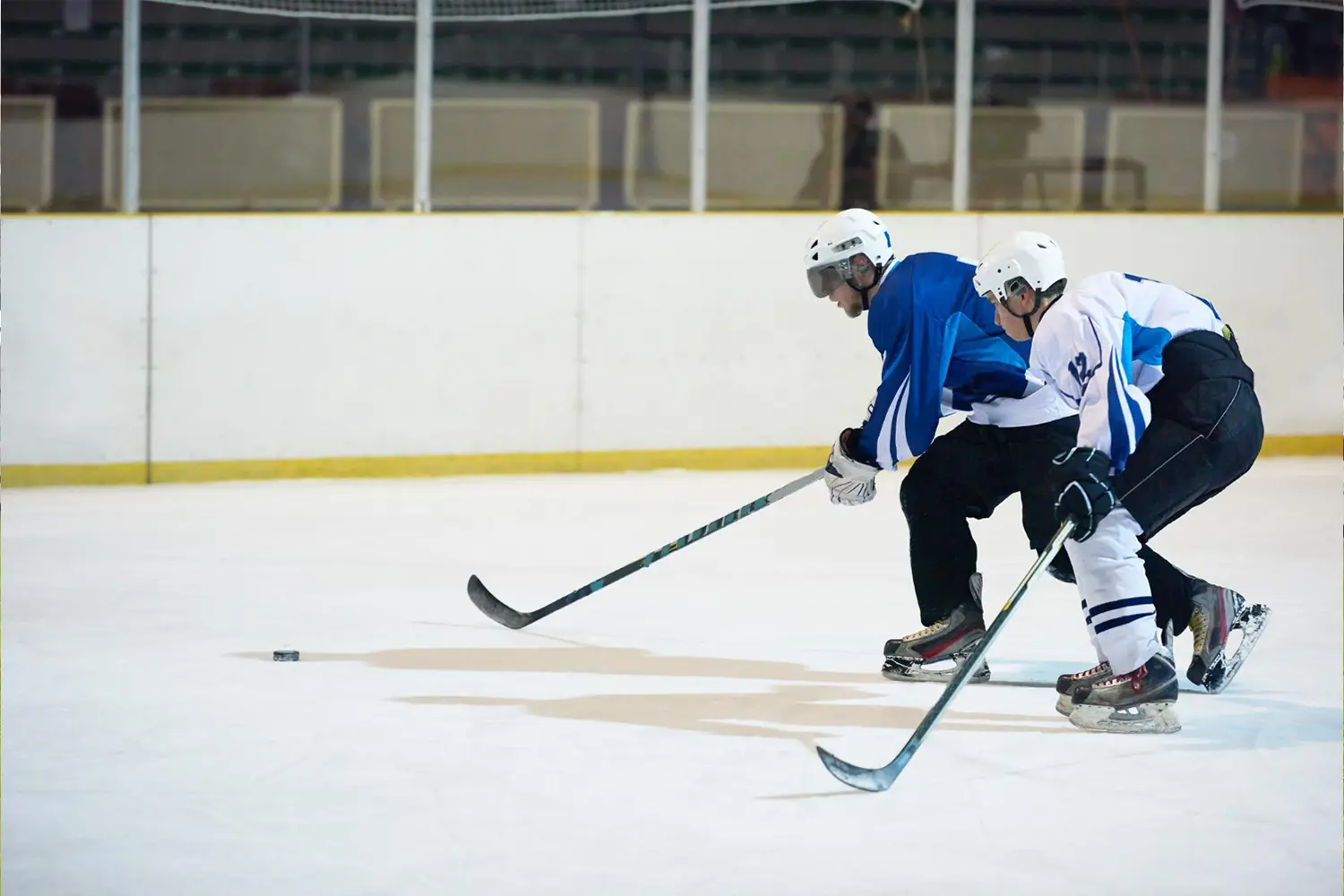 an image of two male hockey players skating towards the puck symbolizing the risks of carrying AML/CTF Penalties in Australia