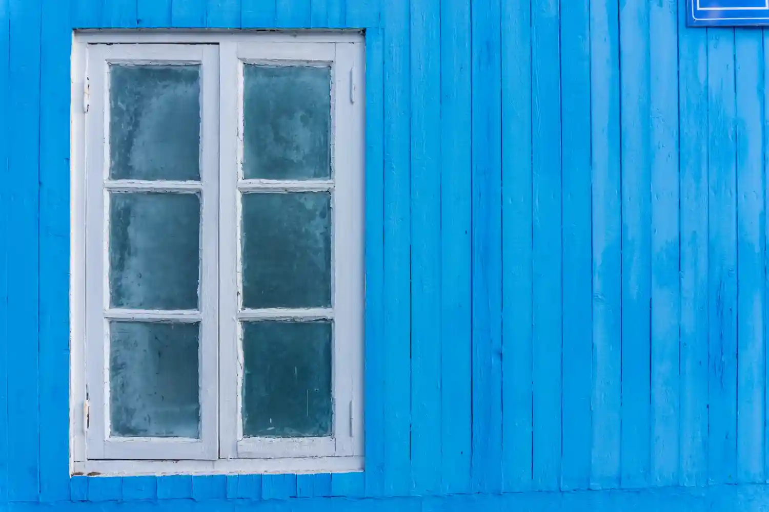 an image of a window on a blue walled house to symbolize the commencement of the AML/CTF Tranche 2 Australia is already here