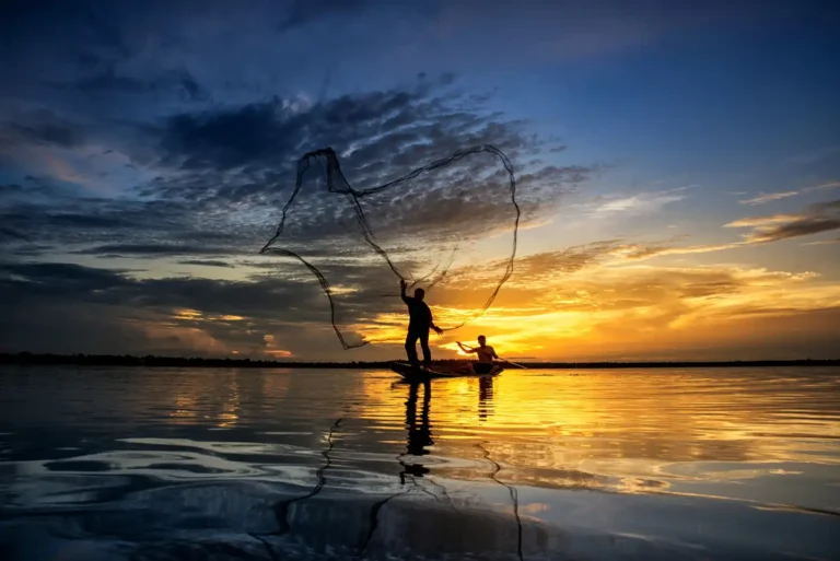 an image of a fisherman throwning a net into the water while the sun sets in the background, symbolising AML/CTF compliance program requirements.