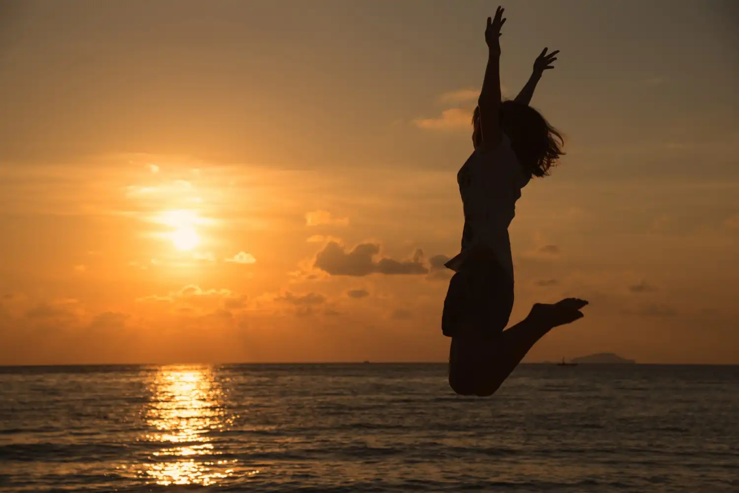 an image of a woman jumping at the beach during sunset, symbolising the
