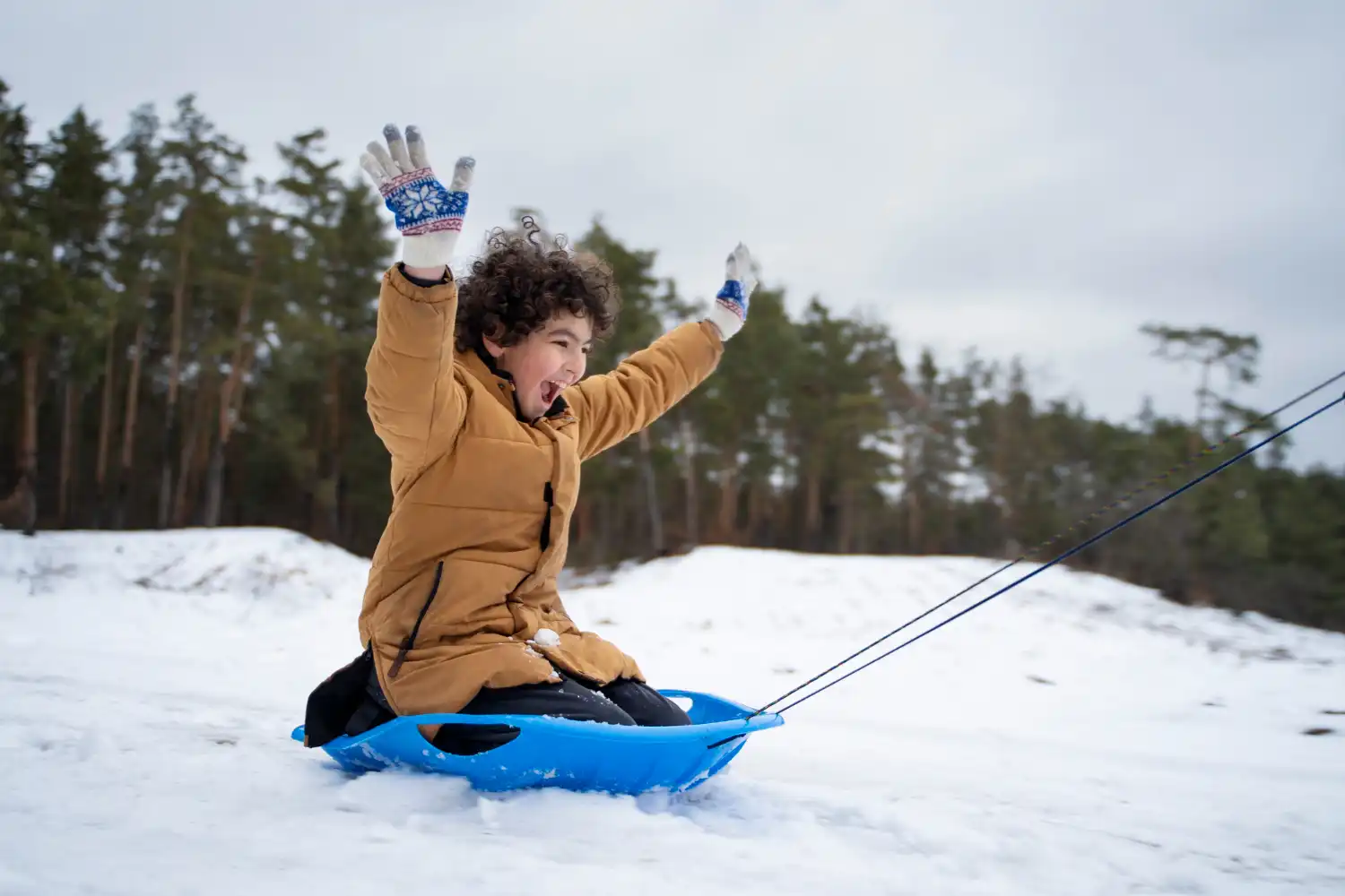 an image of a young boy on a sled playing in the snow, symbolising the peace of mind firms will have when they engage DBA Advisory for the AUSTRAC Audit Process