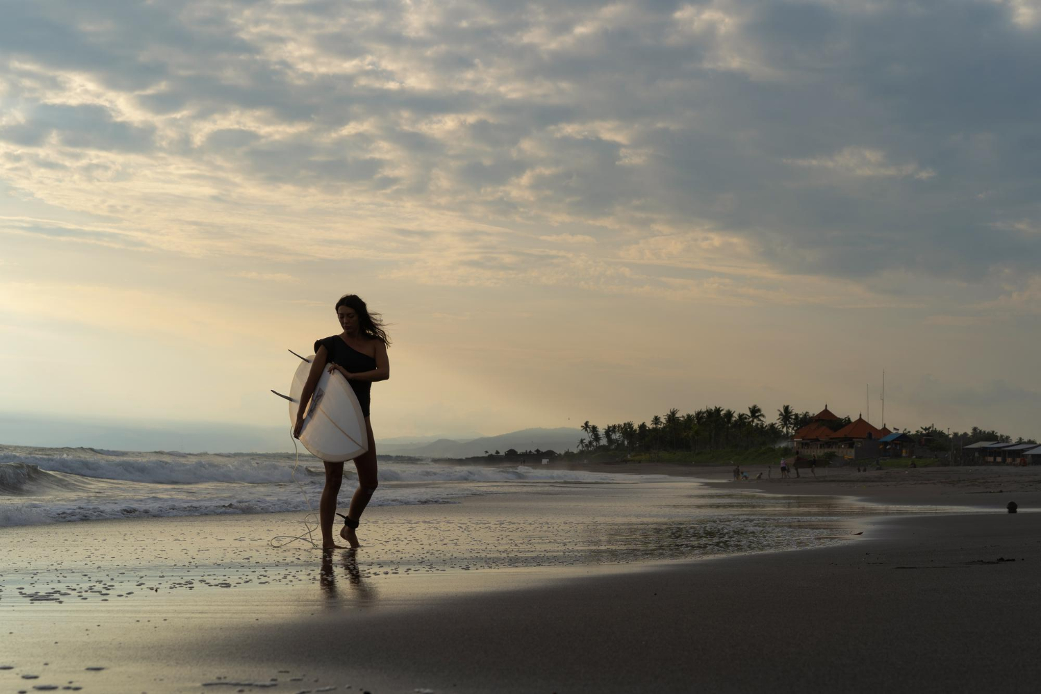 an image of a female surfer walking down the beach, symbolising Australia's small business CGT concessions under Division 152.