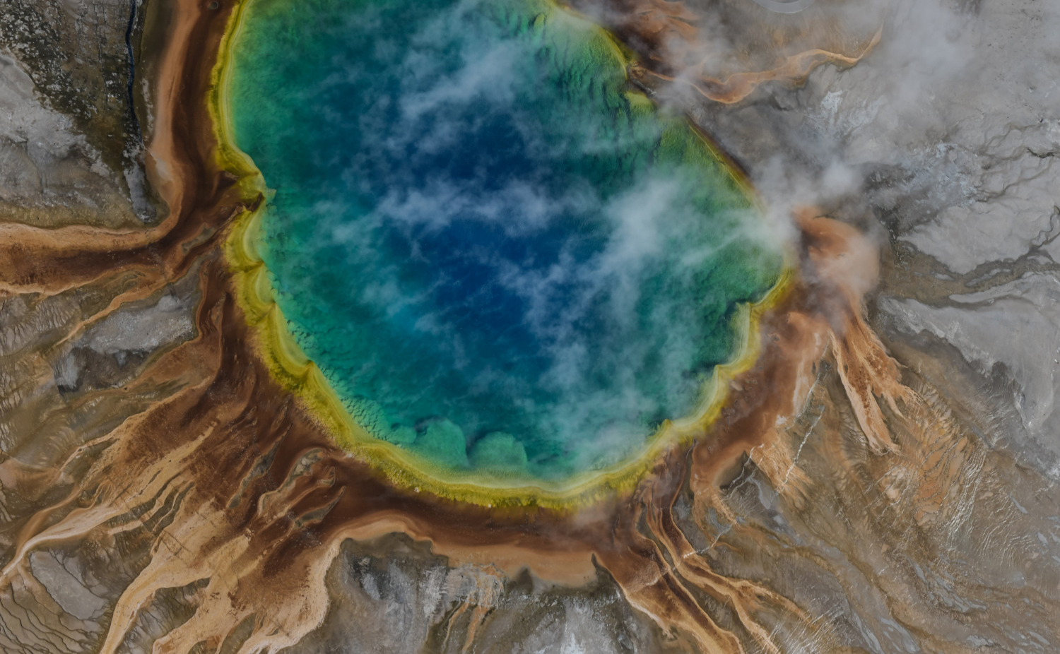 an image of an overhead view of a volcanic crater lake with vibrant blue and green water and steam, symbolising a Suspicious Matter Report