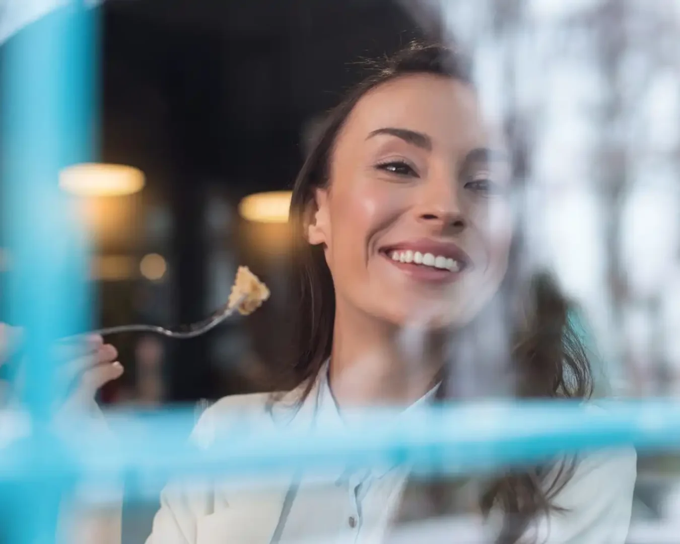 an image of a female cfo smiling through a window while eating cake, symbolising the peace of mind businesses experience with DBA Advisory's Private Enterprise Advisory