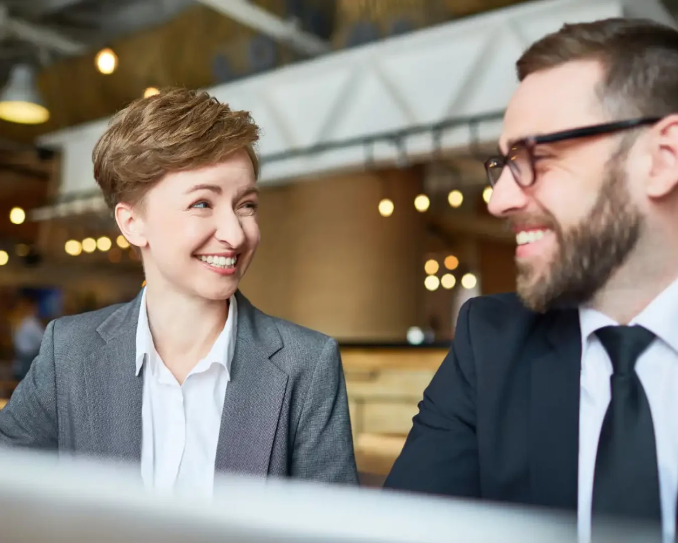 an image of a male and female stuff discussing over the screen portion of a laptop the success of their project, symbolising the significant impacts of a specialised technology and infrastructure advisory.